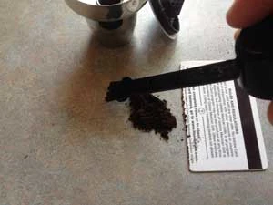 Cleaning up spilt coffee grounds with a brush credit card