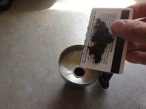 Using a credit card to place coffee grounds in a funnel